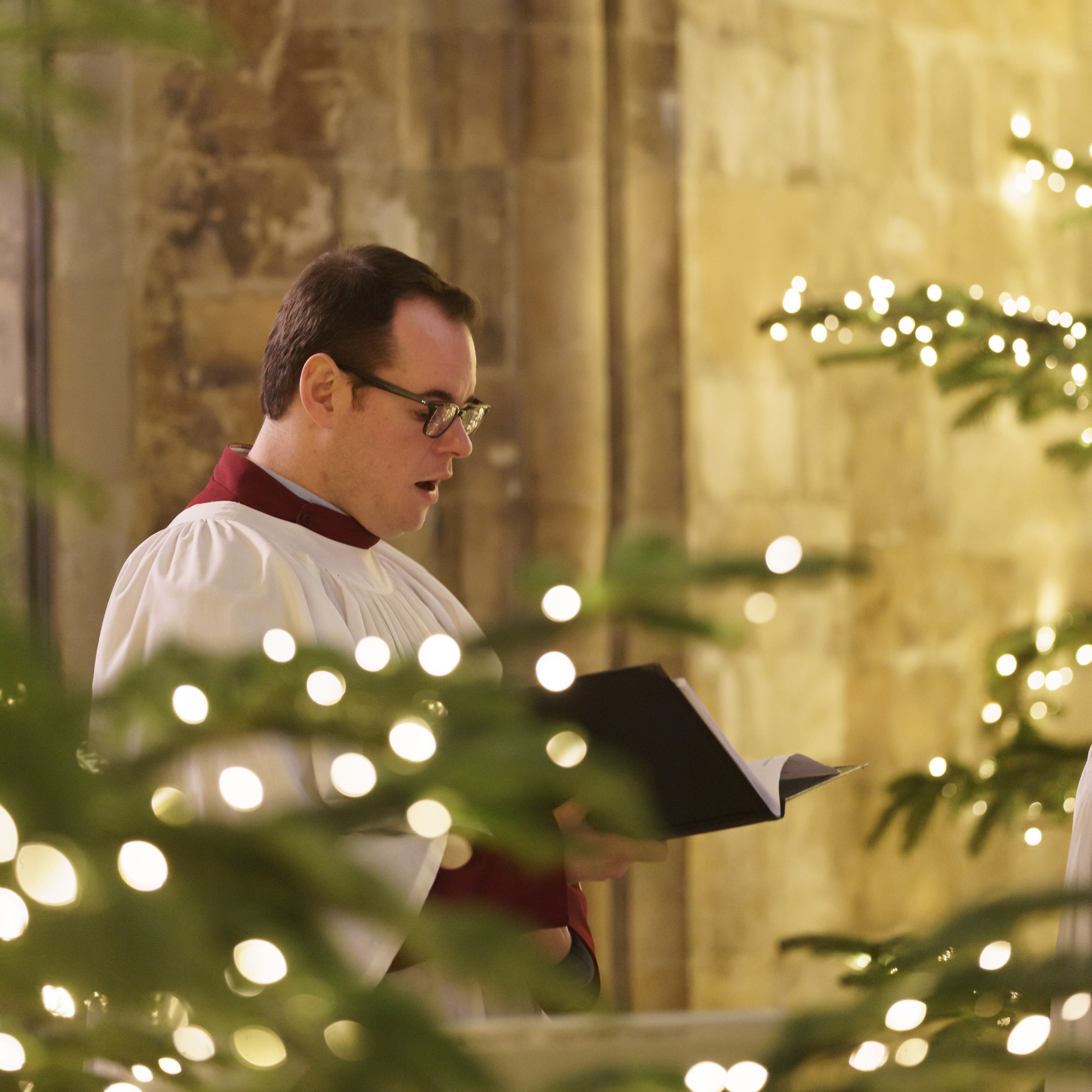 George singing during a carol service next to Christmas lights