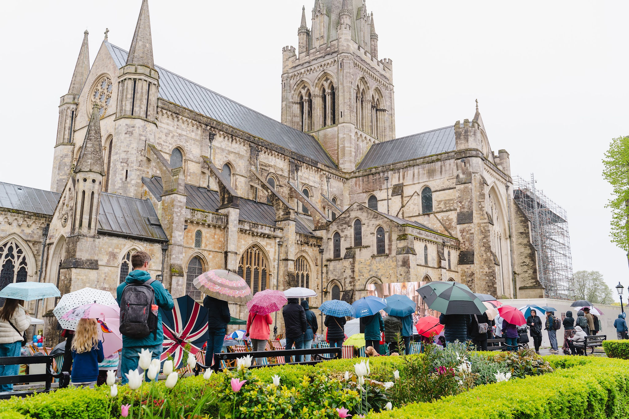 People congregate with umbrellas on the Cathedral Green to watch King Charles coronation