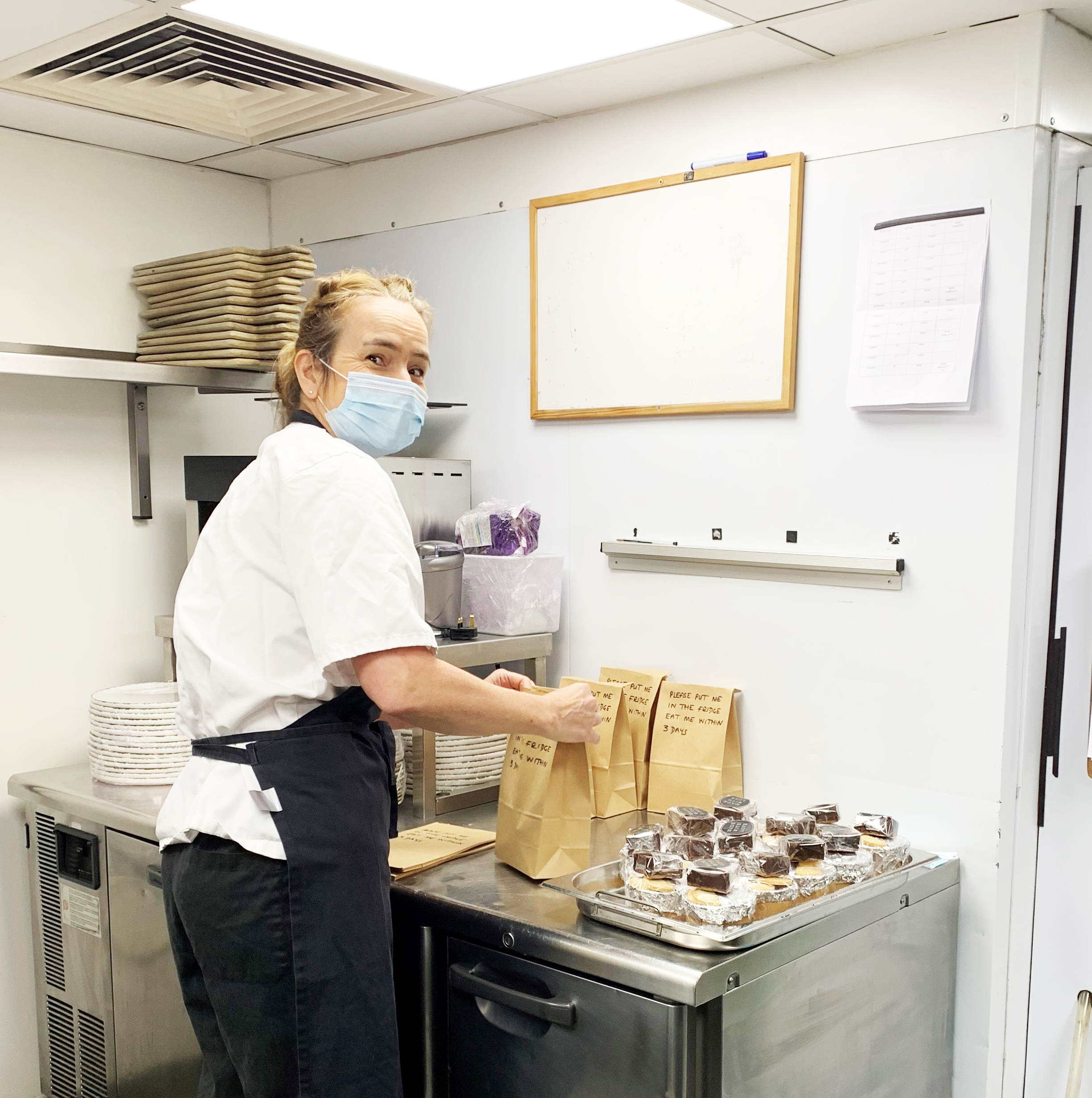 A Chef prepares a meal in a kitchen, smiling at the camera whilst wearing an apron