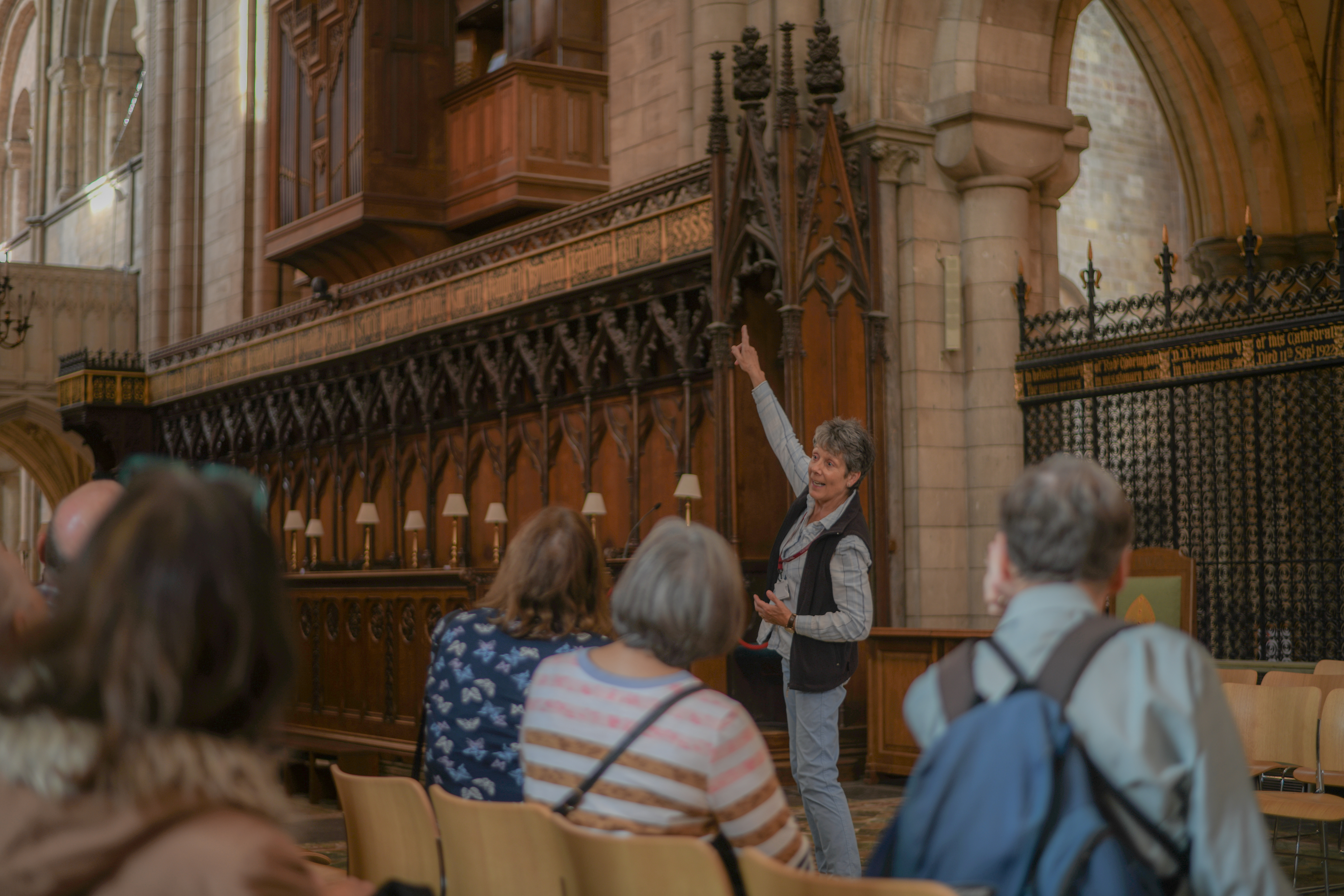 A volunteer guide points to the Quire with a large group