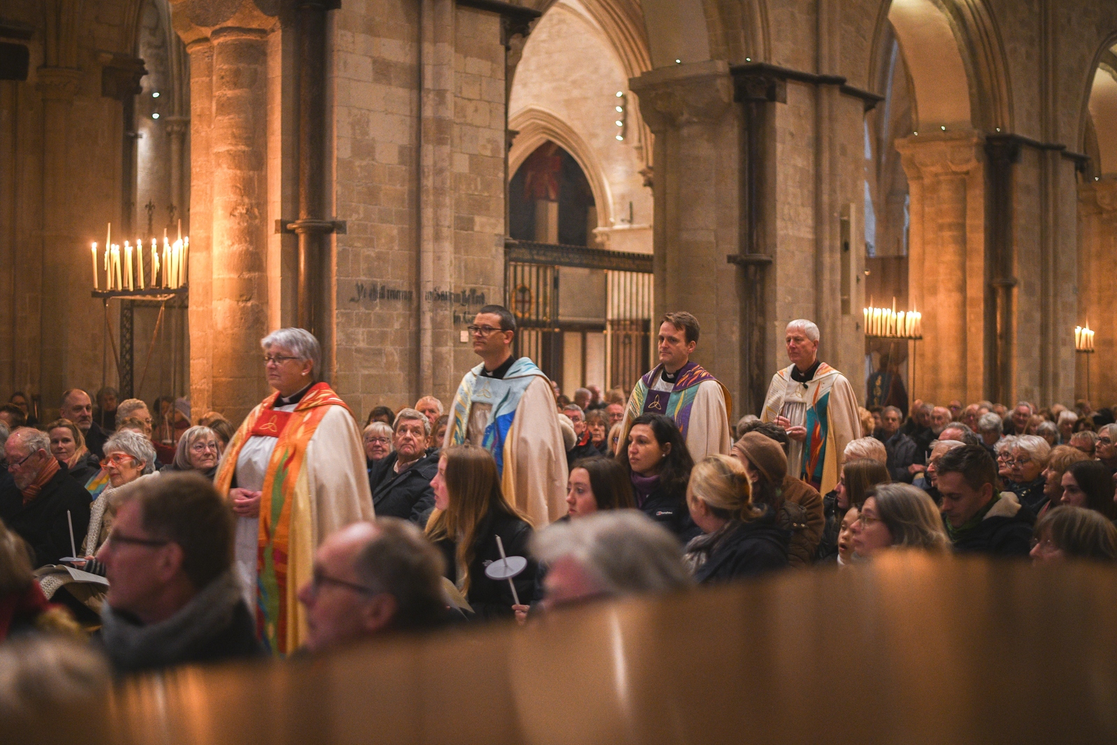 Cathedral Clergy process down the middle of the Nave in between rows of the congregation. Left to right, Canon Treasurer, Canon Chancellor, Canon Precentor and Interim Dean of Chichester)