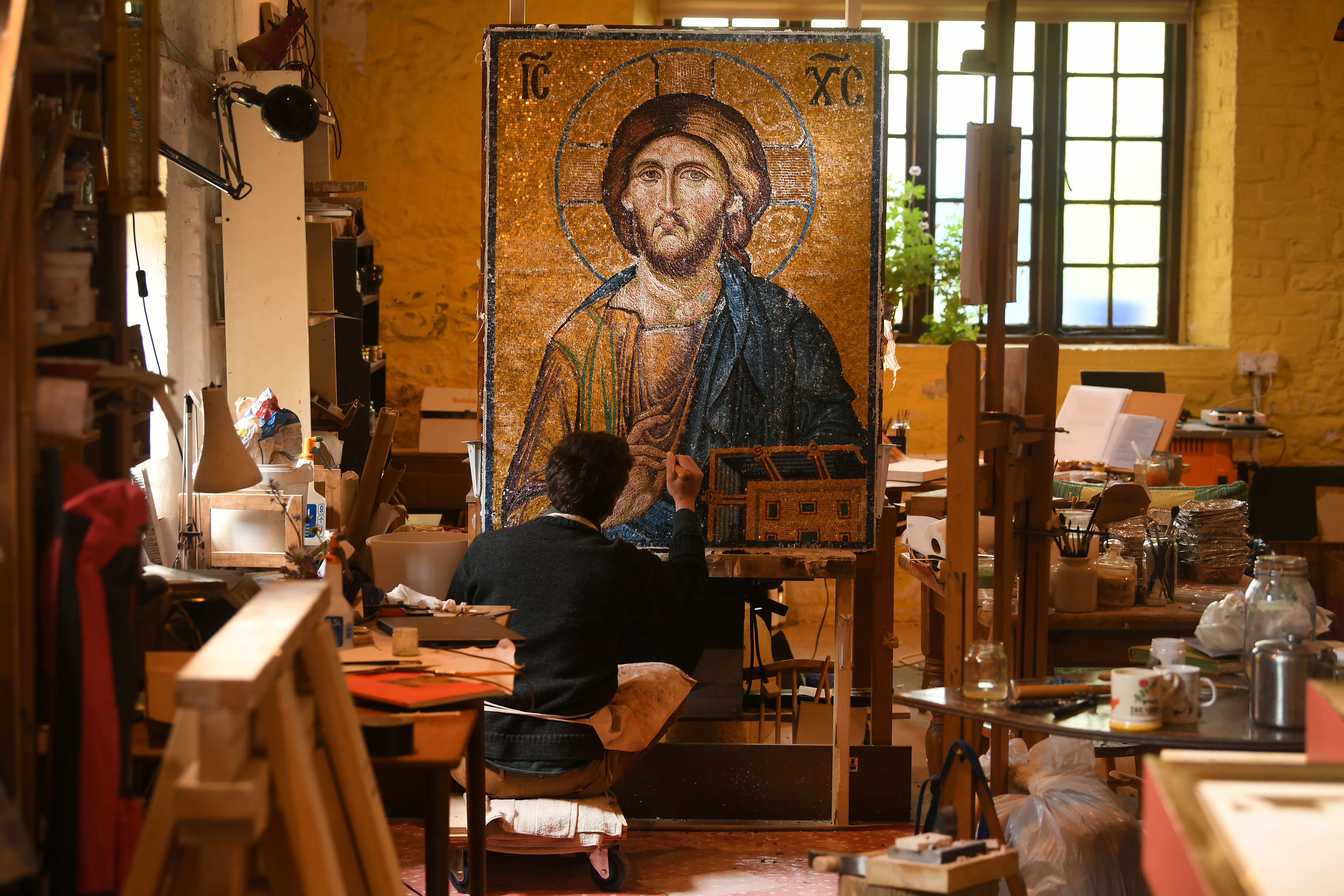 A man with brown hair sits in front of a painted icon