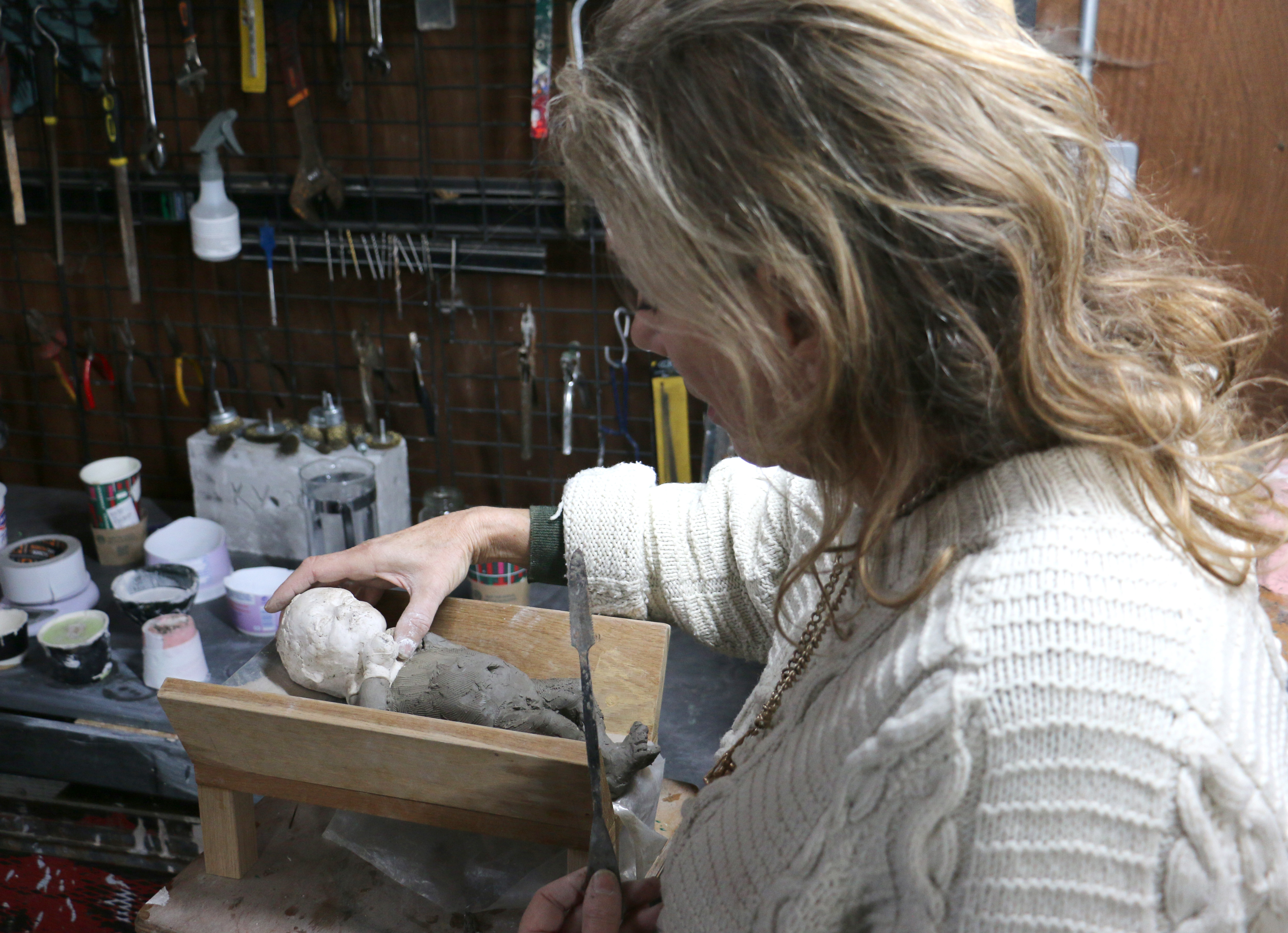Sculptor Kate Viner holds the cast of the Christ child's head to the body during the creation process