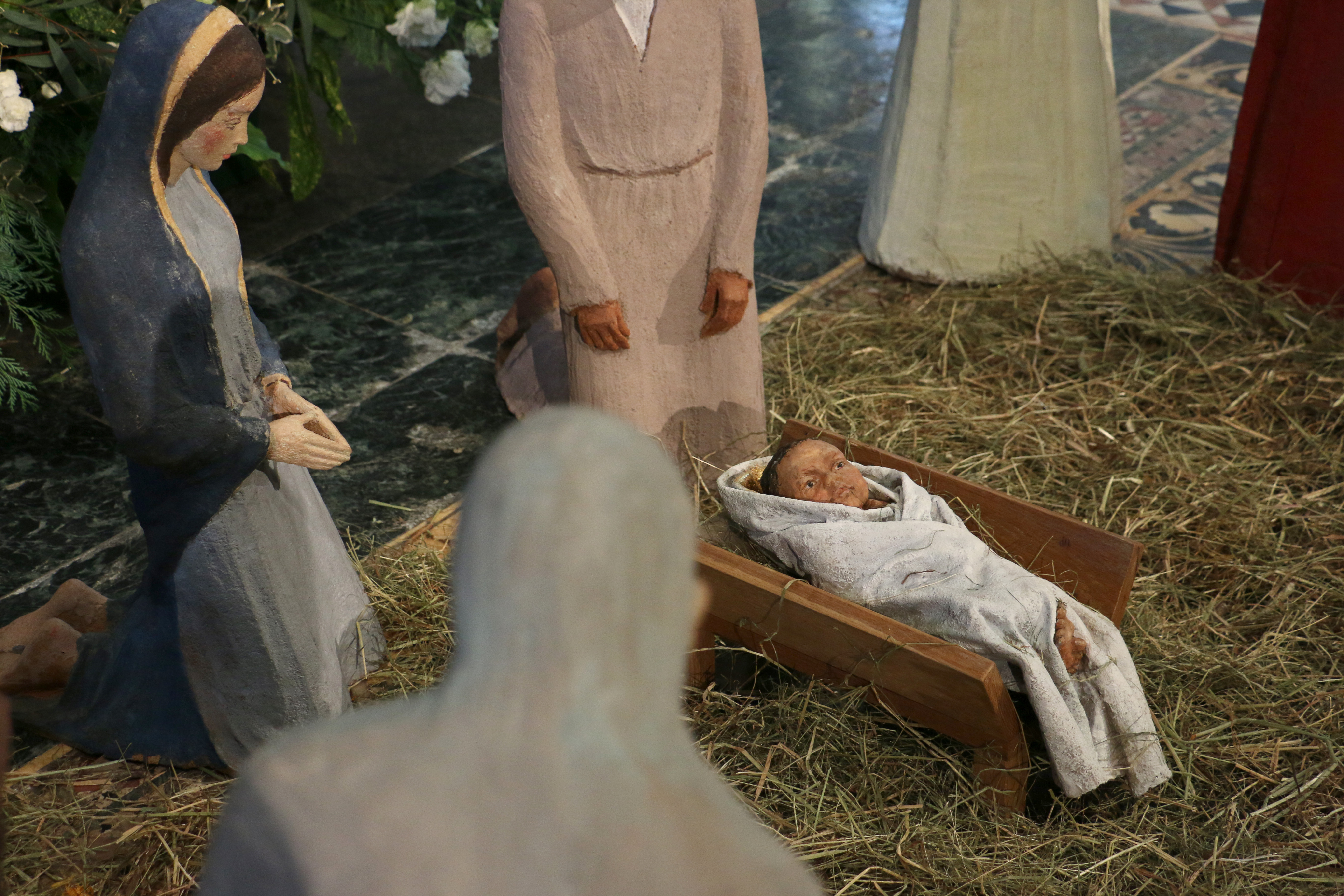 Taken from behind the shoulder of a shepherd sculpture, the Christ child lays in front of Mary and Joseph sculptures