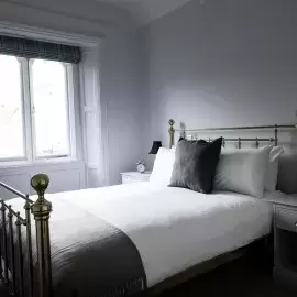 Standard Double grey bed in a neutral white room