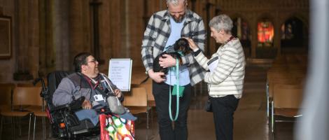 Two welcomers say hello to a man and his dog