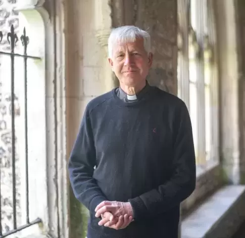 Interim Dean of Chichester, the Reverend Canon Simon Holland stands in the Cloisters, a stone walkway
