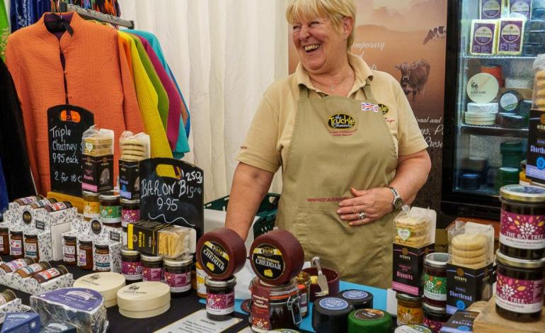 a woman behind a stand selling cheese