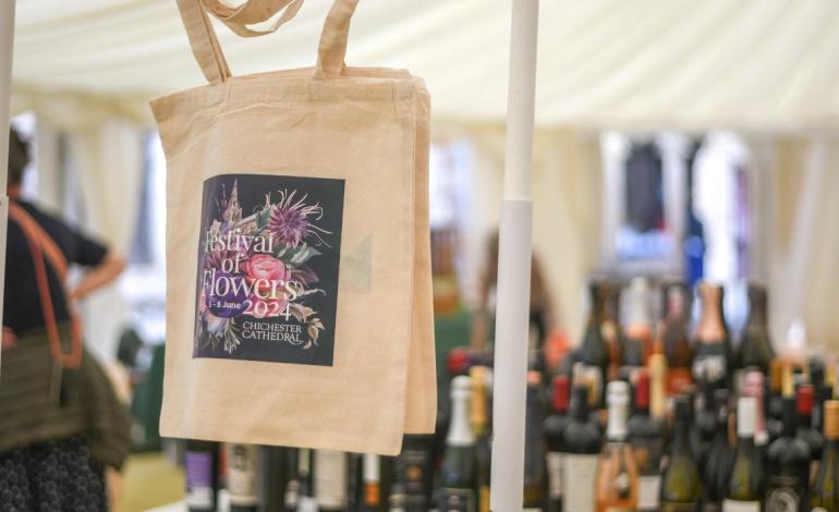 foreground: festival of flowers bag, background: bottles of wine and people