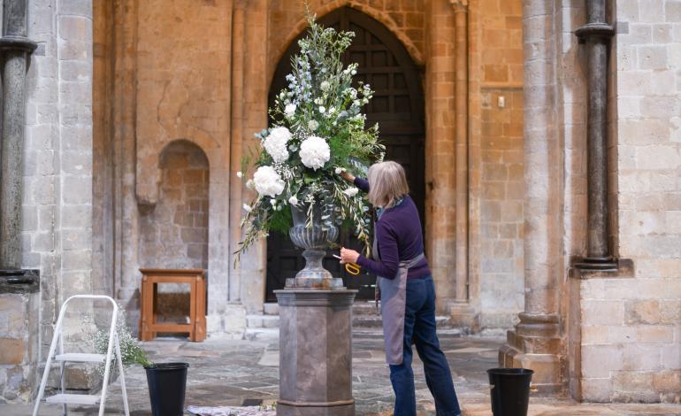 A woman  places white flowers in a floral display bucket