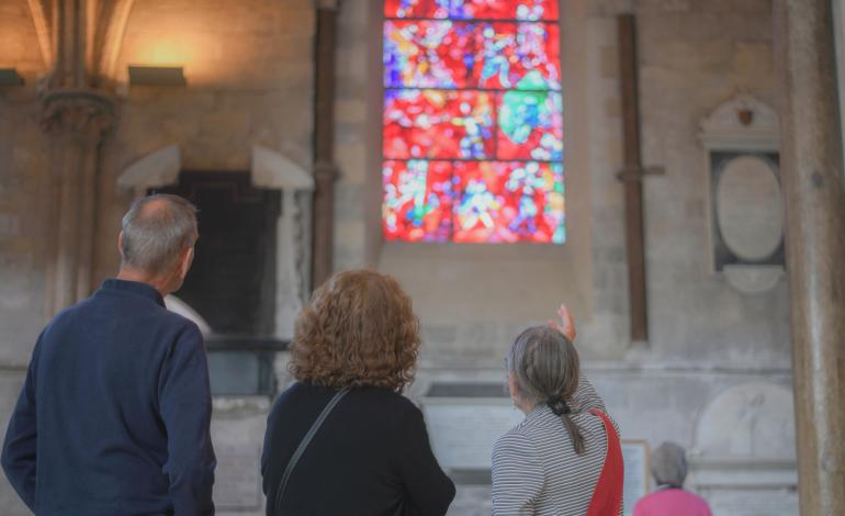 A guide shows a tour group the Chagall window, which has vibrant red stained glass