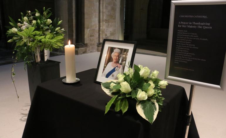 A photograph of  Her Late Majesty Queen Elizabeth II with flowers and a candle