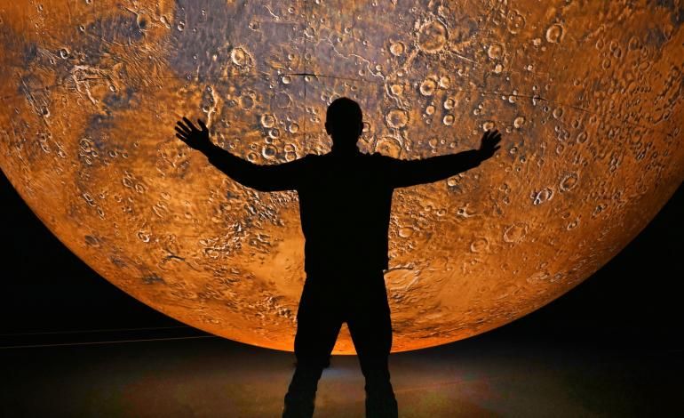 A person stands in front of Mars