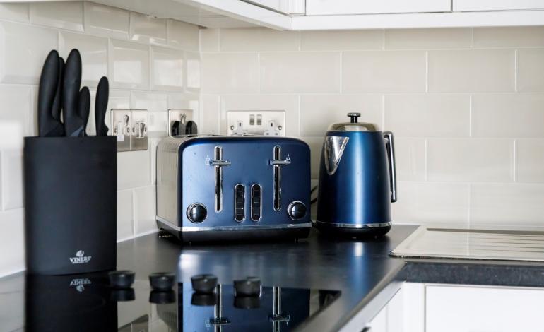 Counter in a kitchen with knife block, kettle and toaster.