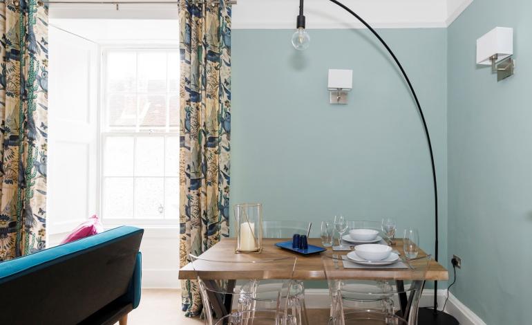 Dining area with large lamp hanging over set dining table. 