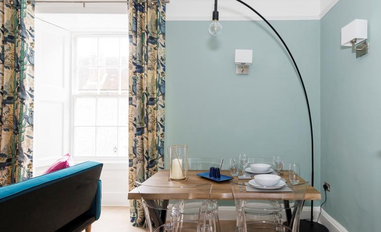 Dining area with large lamp hanging over set dining table. 