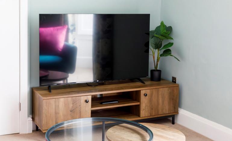 Multimedia view of television with sofa reflected in the glass. 