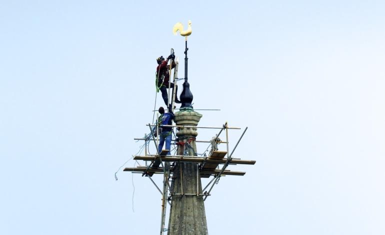 2 people climb the spire to install the new weathervane