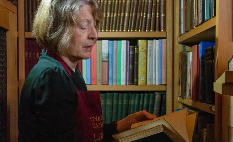 A librarian reads the inside cover of a book to help identify its place on the shelf