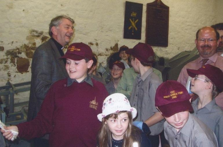 A group of children with two adults standing in front of a white wall