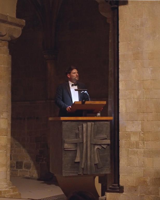 A man in evening dress standing behind a pulpit